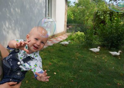 Boy reaching bubble with mother at park