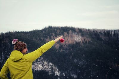 Rear view of man holding bauble against mountain