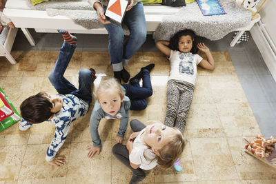 High angle view of children resting while teacher showing triangle on digital tablet