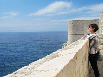 Side view of woman looking at sea against sky