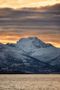 Sun rising behind a snowy mountain on godøy in winter, sunnmøre, møre og romsdal, norway.