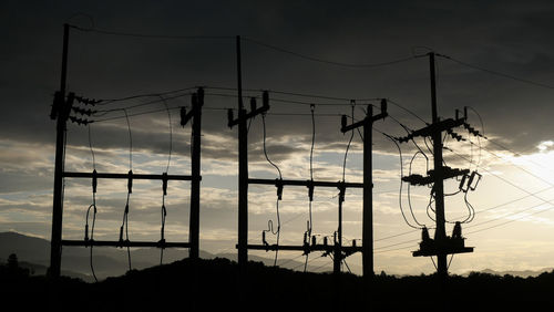 Low angle view of silhouette electricity pylon against sky during sunset