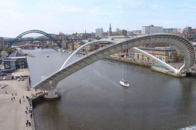 Bridge over river in city against sky