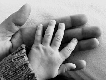 Cropped hands of father and daughter on bed