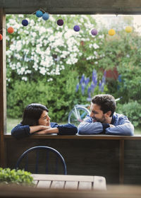 Smiling couple looking at each while leaning on log cabin