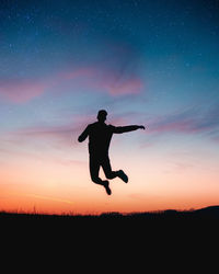 Silhouette man jumping on field against sky during sunset