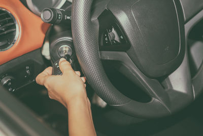 Cropped hand inserting key while sitting in car