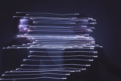 Multiple image of woman with light trails against black background