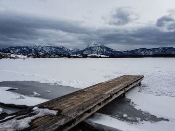 Scenic view of lake by snowcapped mountains against sky