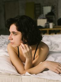 Thoughtful young woman lying on bed