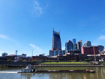 Modern buildings by river against sky in city