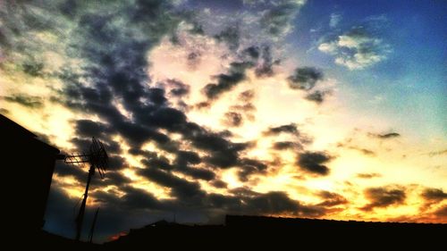 Low angle view of silhouette electricity pylon against sky during sunset