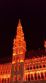 Low angle view of illuminated clock tower at night