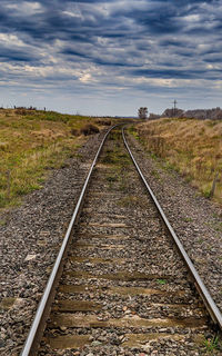 Surface level of railroad tracks on field against sky