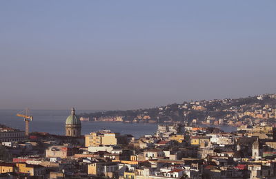 Cityscape by sea against clear sky