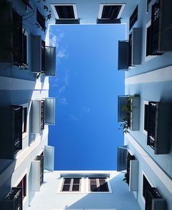 Directly below shot of buildings against blue sky