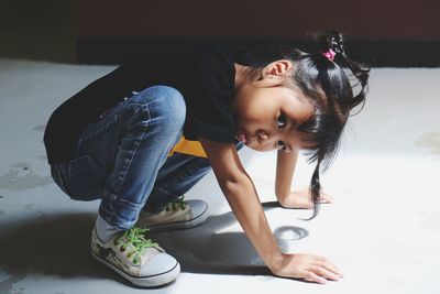 Side view of girl crouching on white floor