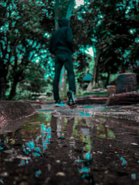 Low section of man walking in park during rainy season