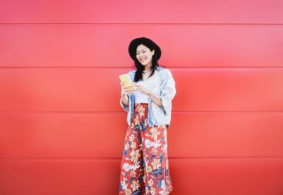 Woman standing against red wall