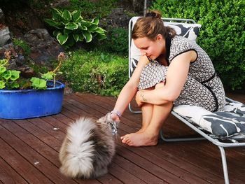 Woman touching cat while sitting at back yard