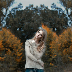 Young woman standing on tree during autumn