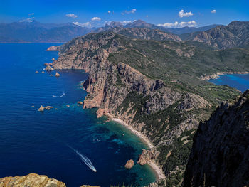 Aerial view of sea and mountains against blue sky