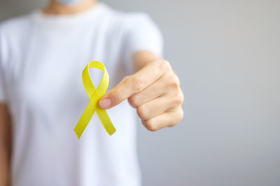 Midsection of woman holding paper against white background