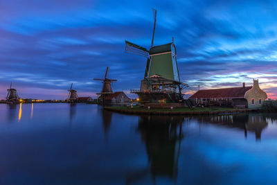 Traditional windmill by water against sky