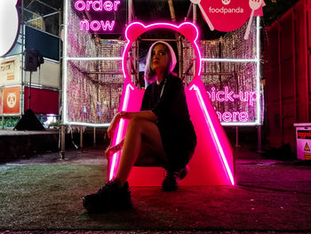 Full length of woman sitting on seat at night