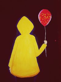 Close-up of yellow balloon against colored background