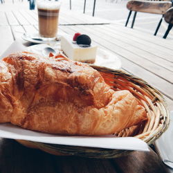 Close-up of croissant with cake and drink served on table
