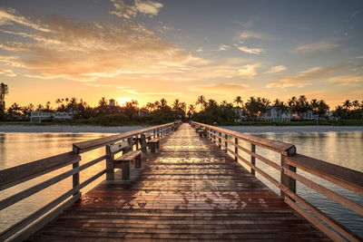 Pier over lake against sky during sunset