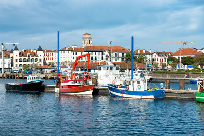 Sailboats moored in sea against buildings in city