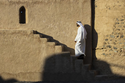 Rear view of man walking on staircase against building