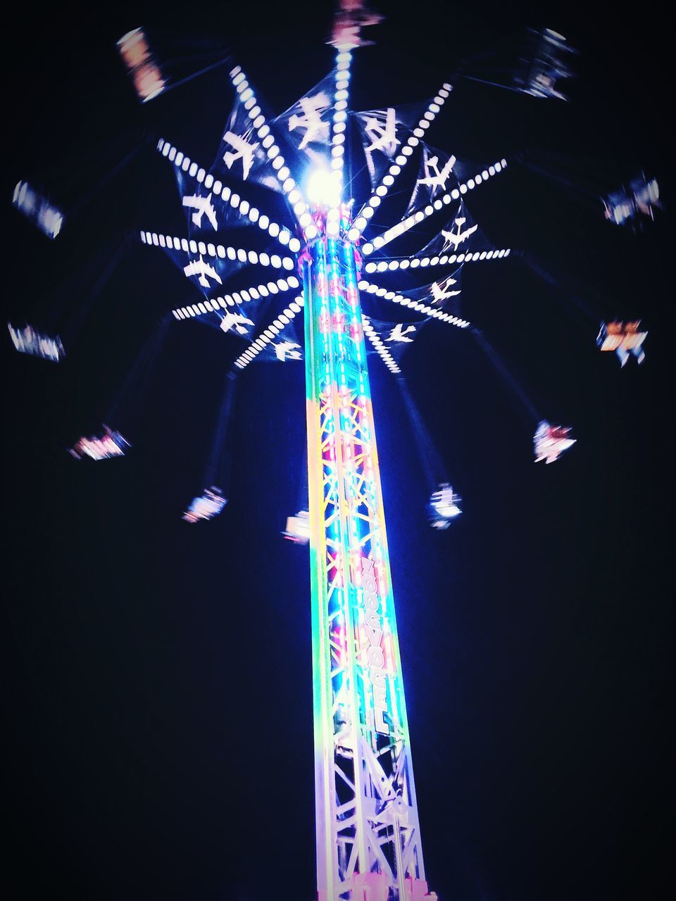 illuminated, night, low angle view, arts culture and entertainment, amusement park ride, amusement park, celebration, multi colored, ferris wheel, sky, glowing, lighting equipment, decoration, event, motion, firework display, traveling carnival, long exposure, built structure, outdoors