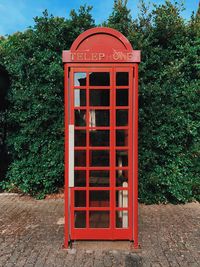 Red telephone booth against trees