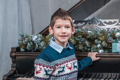 Portrait of smiling boy against piano at home