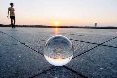 Man with ball on glass against sky during sunset