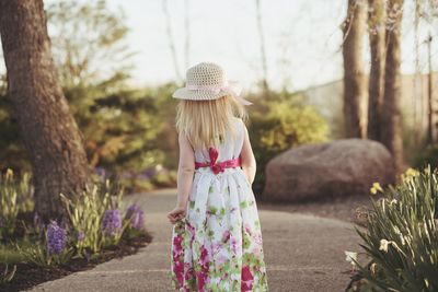 Rear view of girl standing against trees