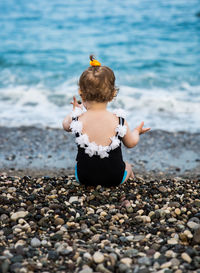 Rear view of baby girl sitting at beach