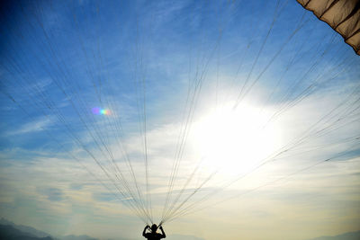 Silhouette woman paragliding against sky during sunset
