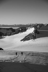 People on snowcapped mountain against sky