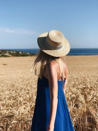 Rear view of woman wearing hat standing on field