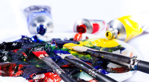 Close-up of paintbrush with paints against white background