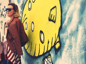 Woman standing against graffiti wall