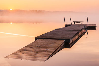 Wooden jetty on still lake at sunrise