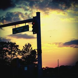 Low angle view of road sign against sky during sunset