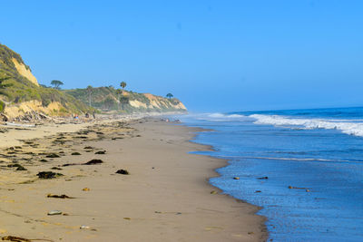 Scenic view of beach against clear blue sky