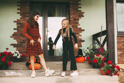 Little sisters celebrate halloween on the street near the house in costumes and make-up