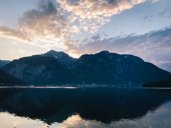 Scenic view of lake by mountains against sky during sunset